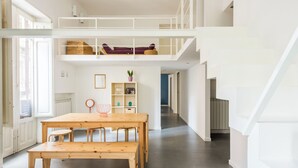 A spacious loft apartment with a high ceiling, a wooden dining table, and a cozy seating area. - Casa Roma nel cuore di Palermo by Wonderful Italy (Palermo)
