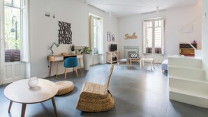 A modern living room with a large window, a desk, a chair, and a staircase. - Casa Roma nel cuore di Palermo by Wonderful Italy (Palermo)