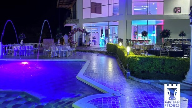 A modern building with a pool area, outdoor seating, and a well-lit entrance. - Finca Hotel Castillo del Toro (Armenia)