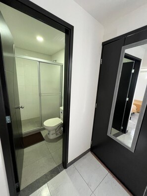 A modern bathroom with a glass shower enclosure, a toilet, and a mirror with a black frame. - Finca Hotel Castillo del Toro (Armenia)