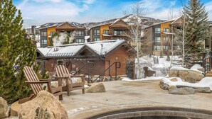 A hot tub area with a wooden deck, large rocks, and a chair.