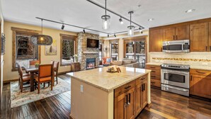 A spacious kitchen with a central island, wooden cabinets, and a built-in microwave.