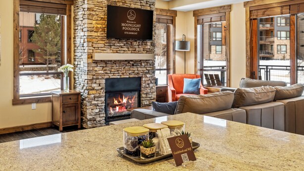 A cozy living room with a stone fireplace, a comfortable sofa, and a coffee table with a tray of amenities.