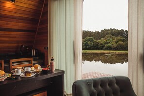 Un coin repas avec une table dressée pour le petit-déjeuner, une vue sur un lac et un intérieur en bois.