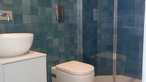 Un baño con un lavamanos blanco, un inodoro y una cabina de ducha con paredes de vidrio.