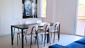 Una cocina moderna con armarios blancos, una mesa de comedor con sillas y un sofá azul.