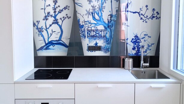 Una cocina con estufa moderna, un lavamanos y paneles decorativos de cerámica azul.