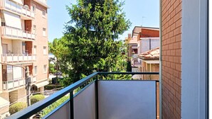 Un edificio residencial con balcones, un árbol y edificios vecinos.