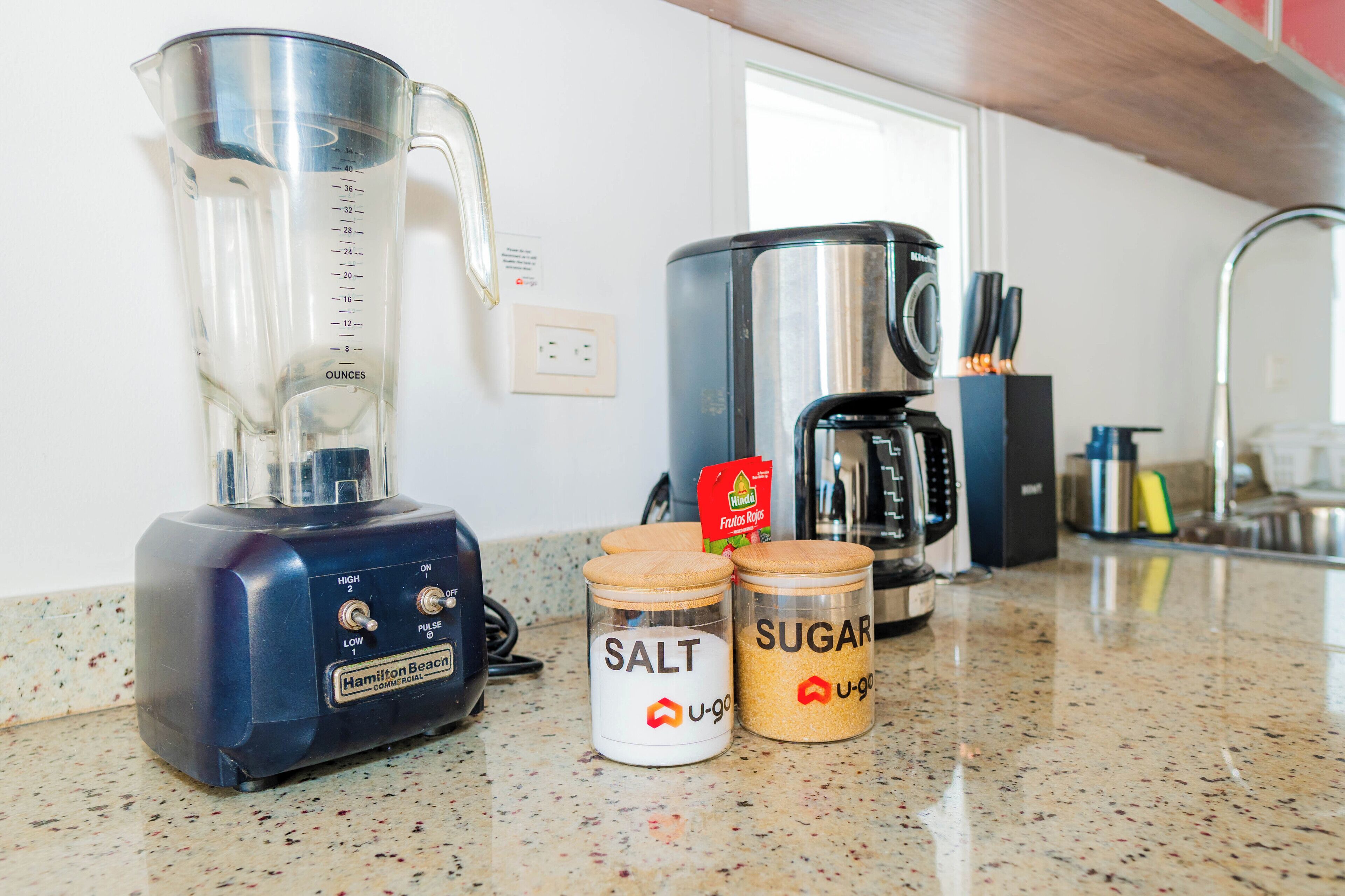 A kitchen counter with a blender, salt and sugar containers, and a coffee maker.
