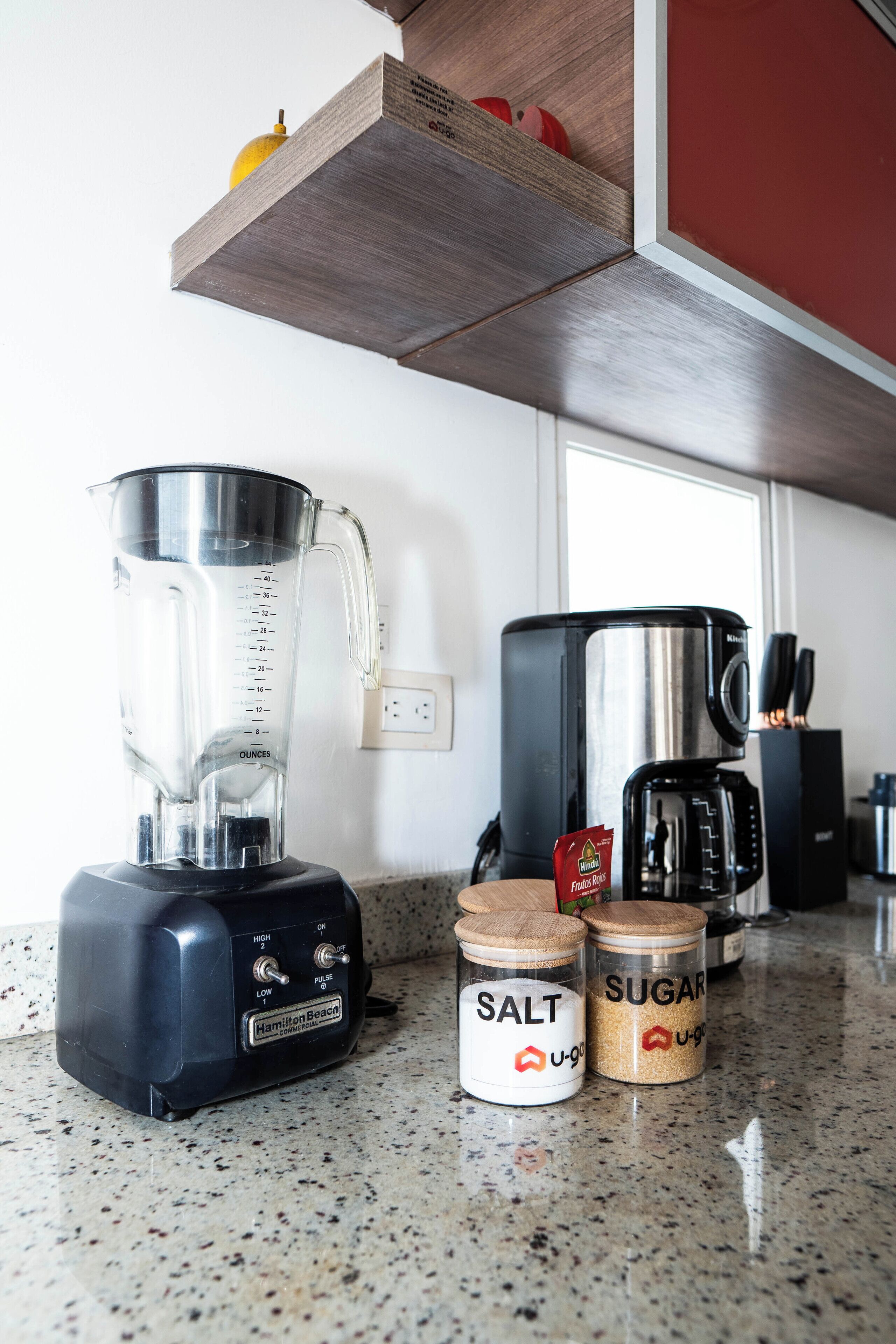 A kitchen counter with a blender, a coffee maker, and two spice jars labeled "salt" and "sugar".