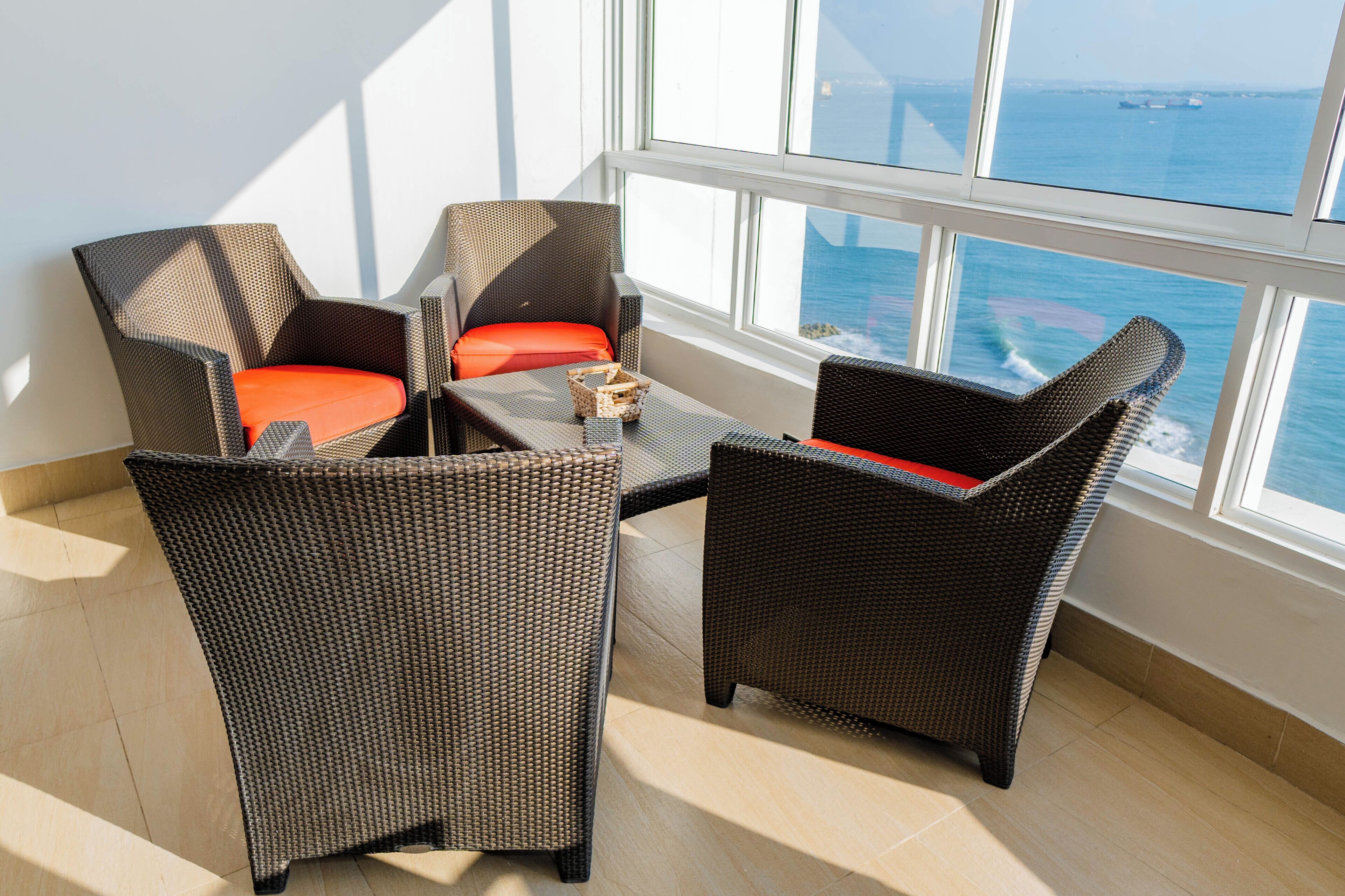 A balcony with wicker furniture and a view of the sea.