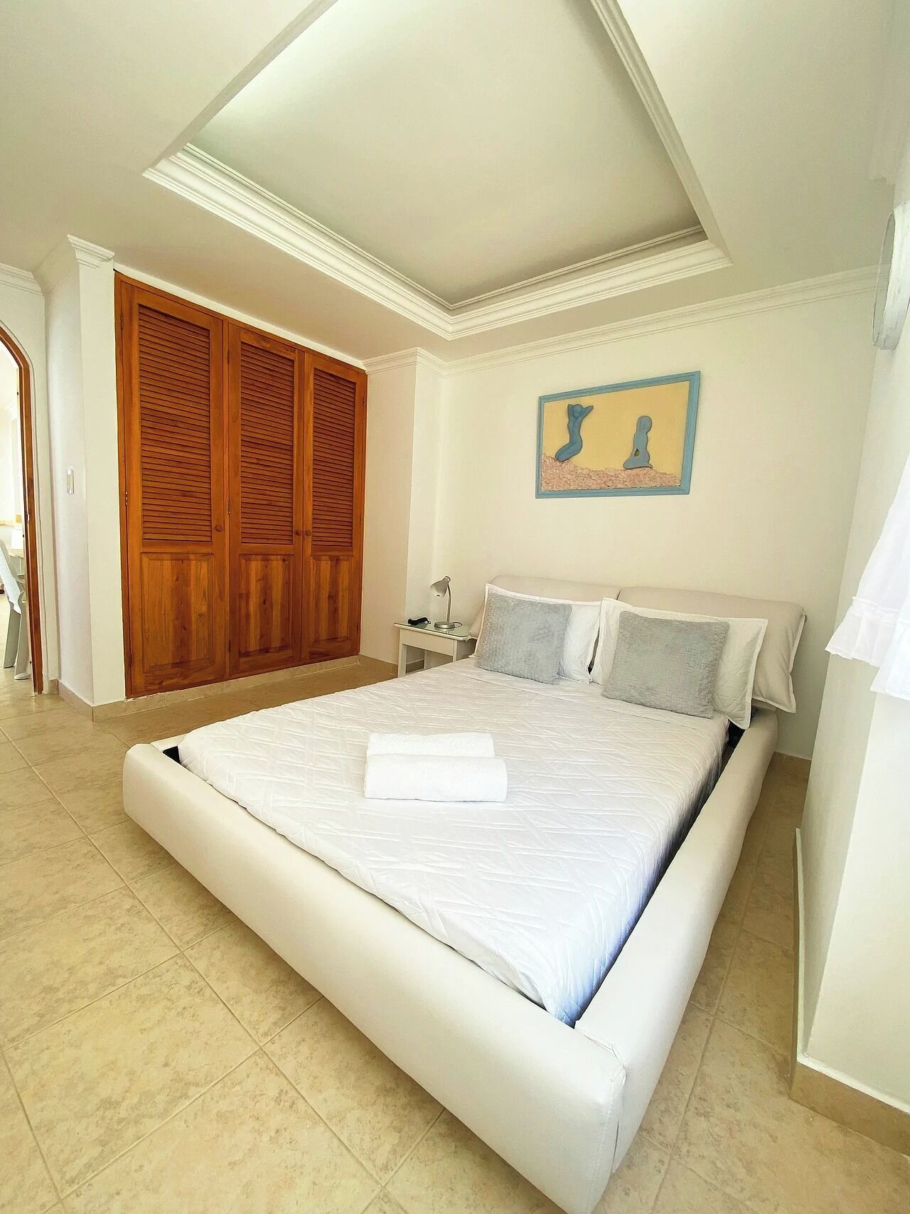 Quarto com cama grande, guarda-roupa de madeira e um quadro na parede.