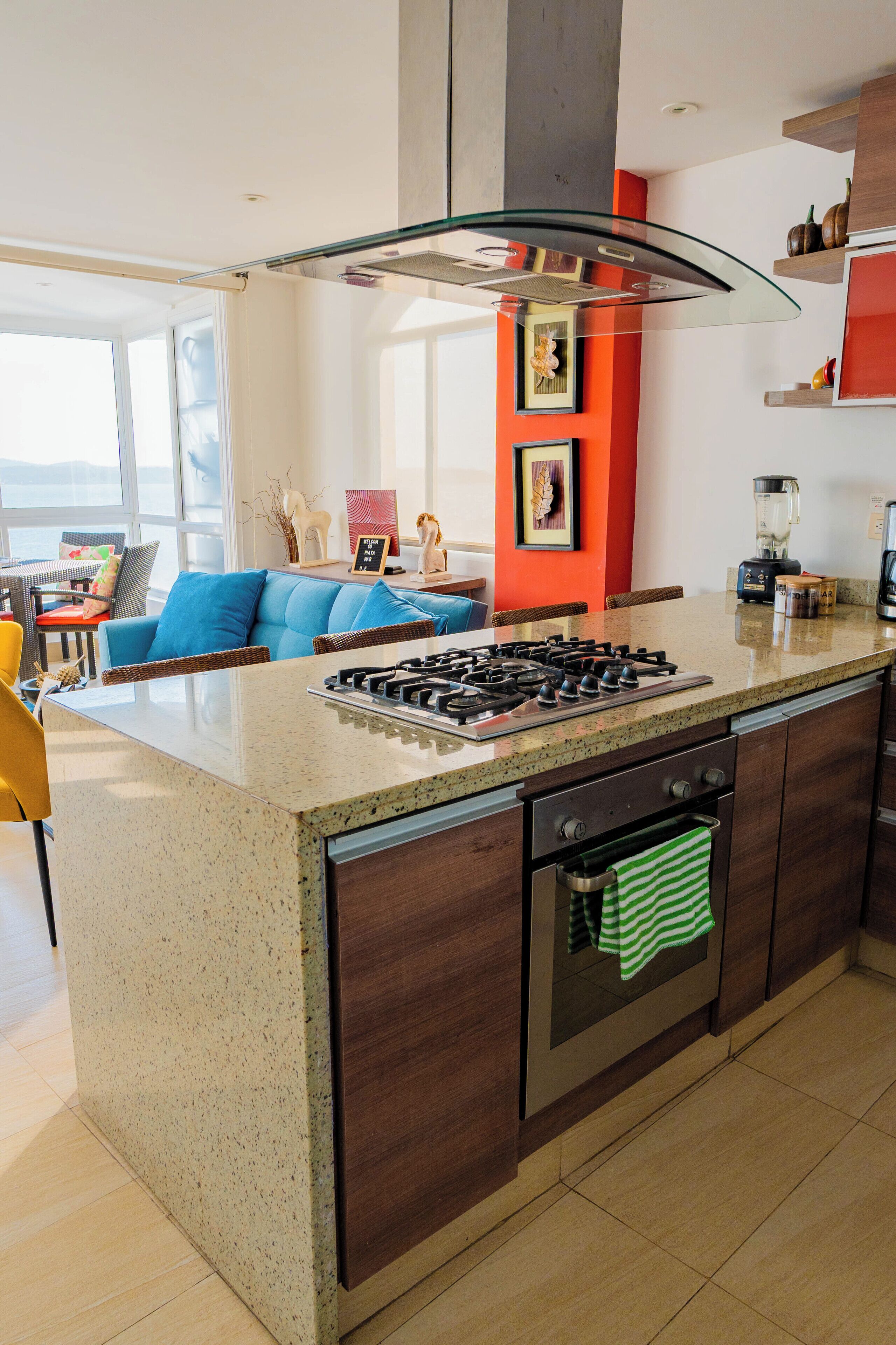A modern kitchen with a central island, a gas stove, and a built-in oven.