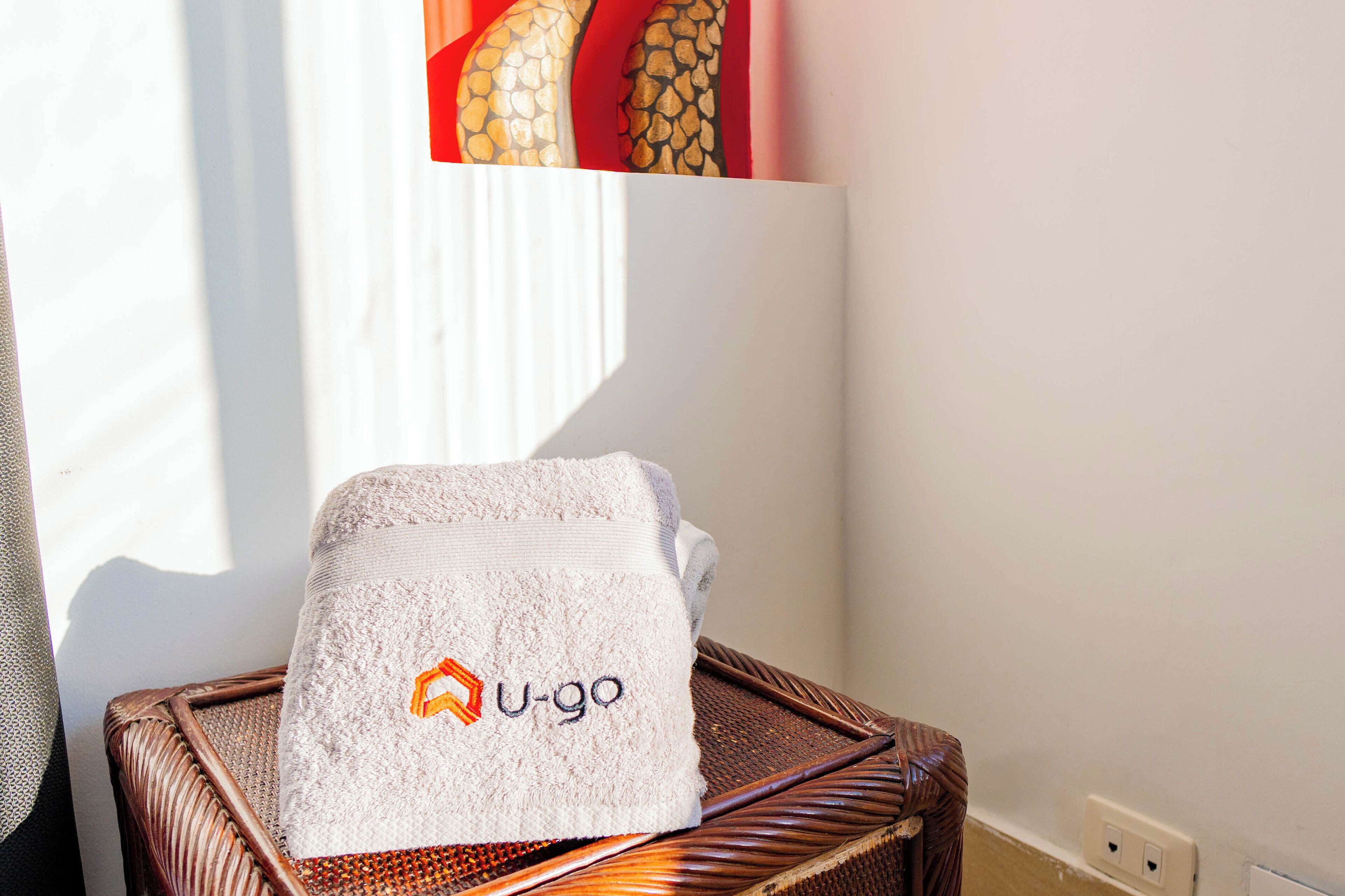 A white towel with a logo on a wicker chair near a window.