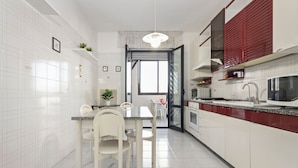 A modern kitchen with white cabinets, a granite countertop, and a dining area with white chairs. - Casa Giovanna by Wonderful Italy (Bari)