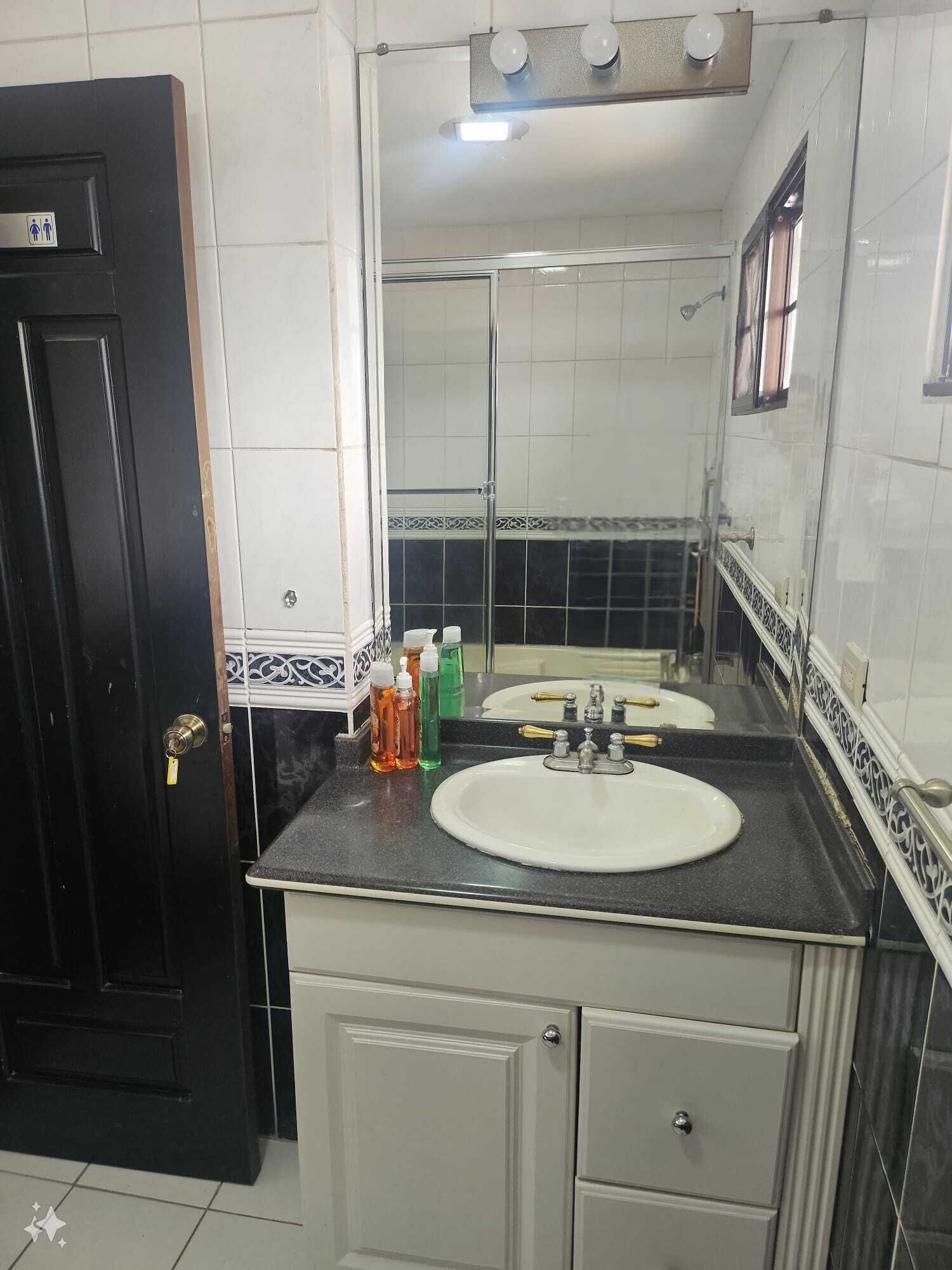 A bathroom with two sinks, a mirror, and toiletries on the countertop.