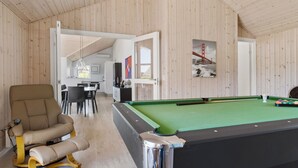 Habitación con mesa de billar, sillón de masajes y zona de comedor con vistas al exterior.