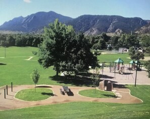 A park with a playground, picnic areas, and a large tree.