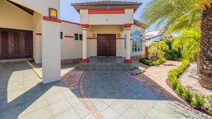 A building with a central entrance, columns, and a tiled patio area. - Sleeps 11 6 Bedrooms Privatepool Outdoor Dining (Noord)