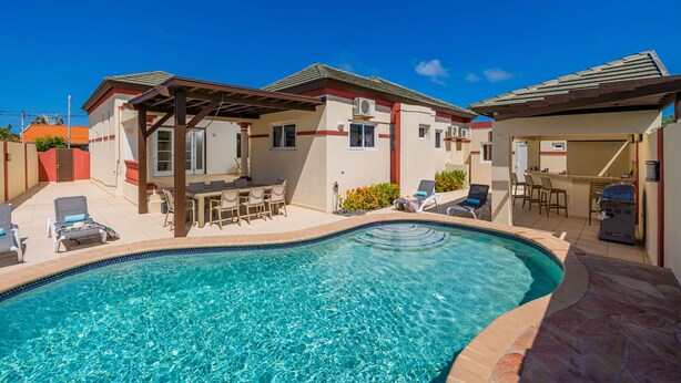 A swimming pool with lounge chairs and a covered patio area. - Sleeps 11 6 Bedrooms Privatepool Outdoor Dining (Noord)