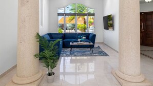 A spacious lobby with high ceilings, large columns, a blue sofa, and a potted plant. - Sleeps 11 6 Bedrooms Privatepool Outdoor Dining (Noord)