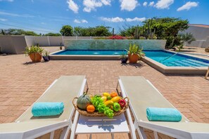 A pool area with two lounge chairs, a fruit basket, and potted plants. - Spacious 4BR Villa Private Pool Cozy Location (Oranjestad)