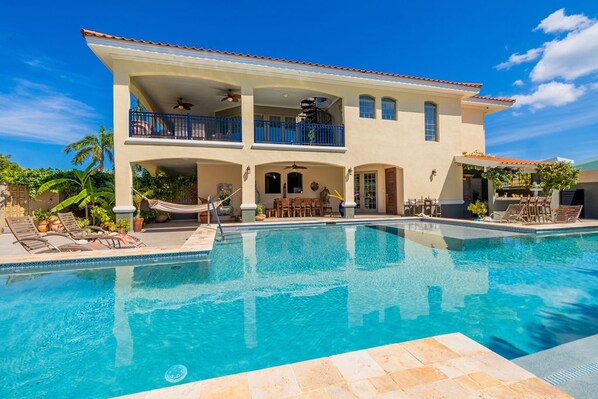 A two-story house with a swimming pool, outdoor furniture, and a hammock. - Ocean View 5BR Villa Steps to Beach Privatepool (Noord)