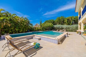 A swimming pool with lounge chairs and a tiled deck. - Ocean View 5BR Villa Steps to Beach Privatepool (Noord)