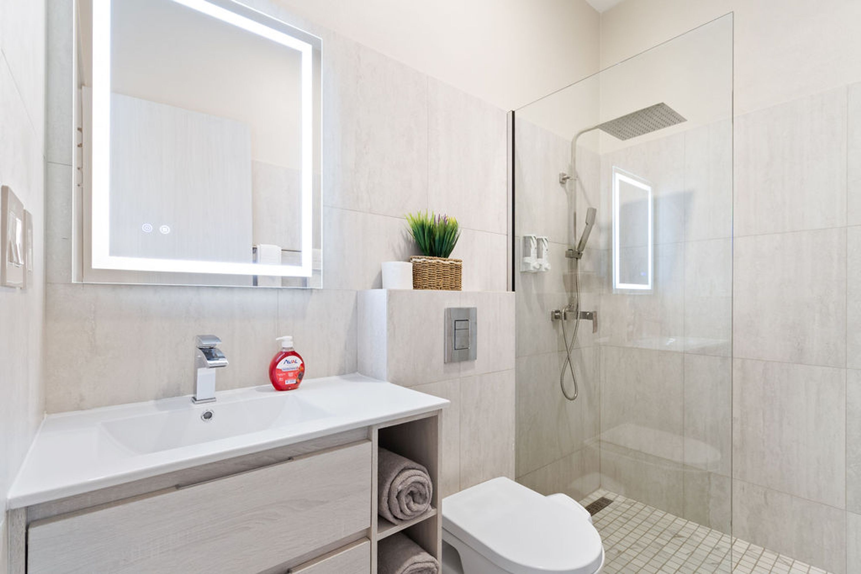Ein modernes Badezimmer mit Waschbecken, Spiegel, Dusche und Toilette.