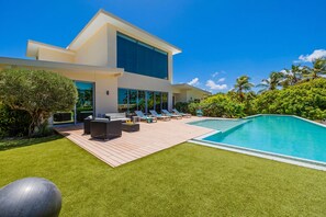 A modern house with a swimming pool, outdoor furniture, and lush greenery.