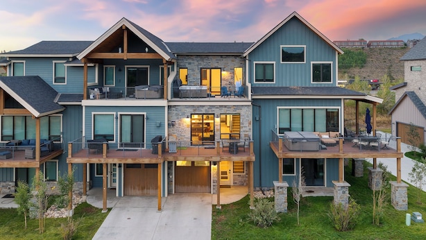 Een modern, meerlaags huis met een overdekt terras, een gevel van natuursteen en grote ramen.