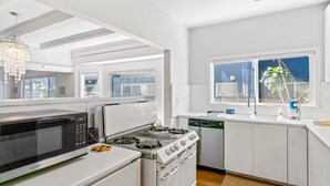 A modern kitchen with white cabinetry, a gas stove, a microwave, and a dishwasher. - Long Beach Condo Home -Minutes Walk To The Beach (Long Beach)