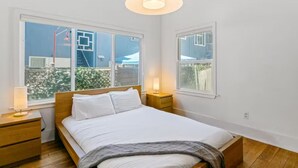 A bedroom with a bed, bedside tables, and a large window. - Long Beach Condo Home -Minutes Walk To The Beach (Long Beach)