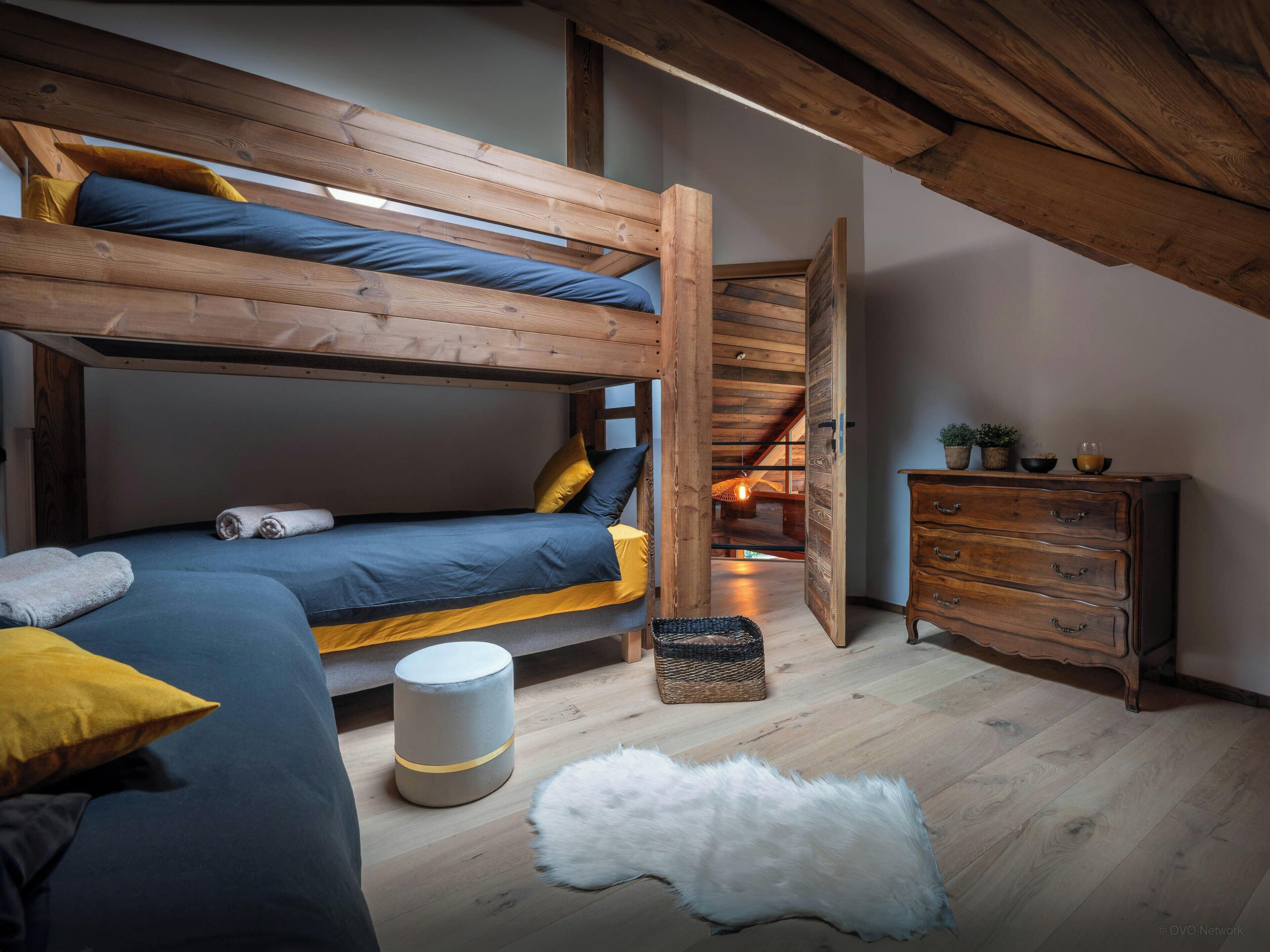 Una habitación acogedora con una litera, un aparador y una alfombra pequeña.