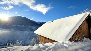 A wooden cabin with a snow-covered roof, surrounded by a snowy landscape and mountains. - Chalet Emeraude des Alpes - peaceful break in the mountains - OVO Network (Saint-Pierre-d'Entremont)