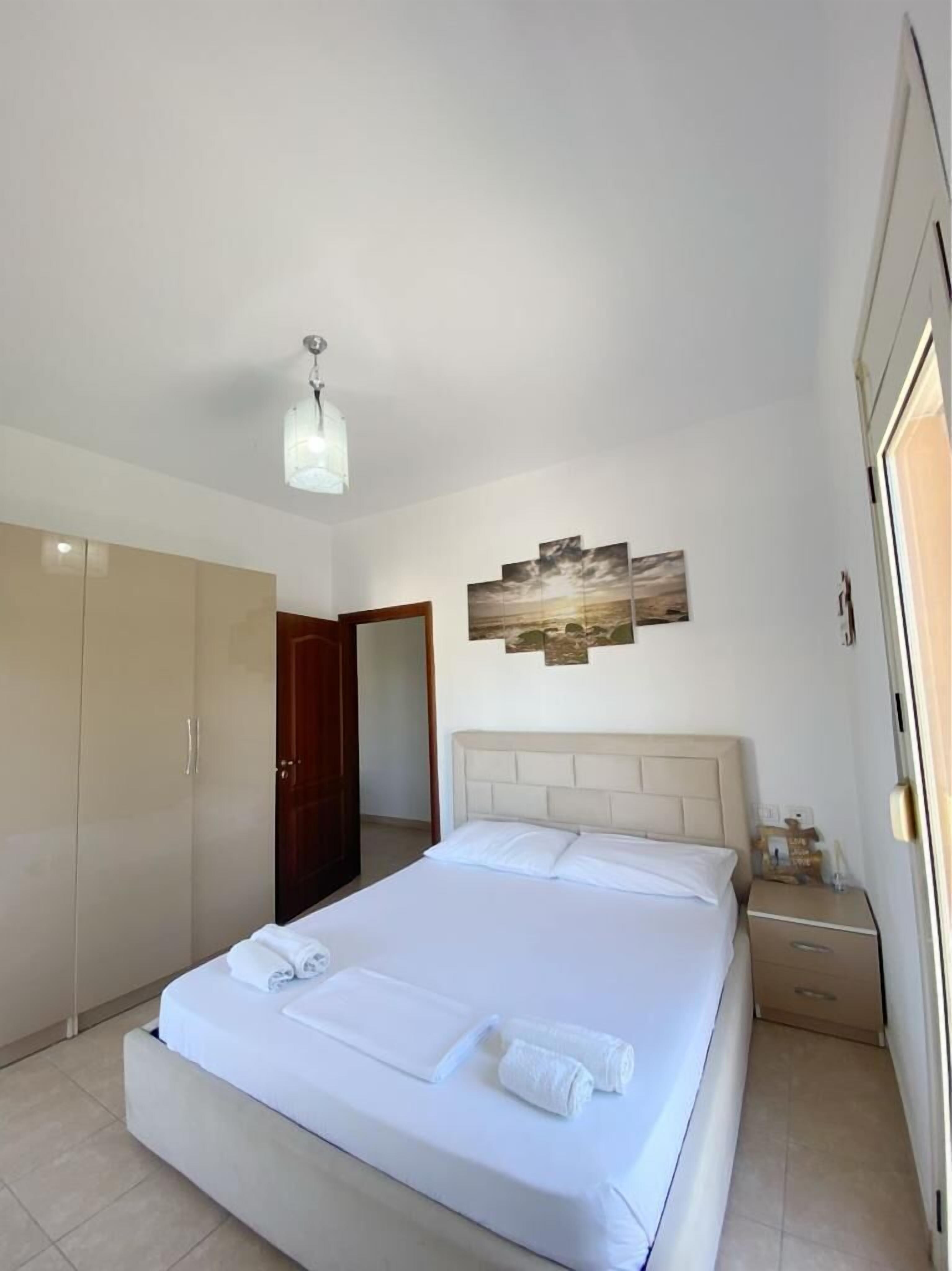 A hotel room with a large bed, a wardrobe, a nightstand, and a painting on the wall.