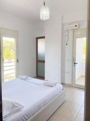 Ein Schlafzimmer mit Bett, Tür und Blick ins Freie.