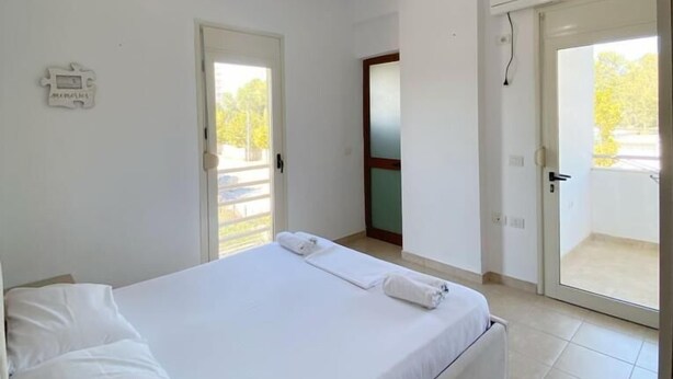 Una camera da letto con un letto, una lampada a sospensione, una porta e vista sull'esterno.