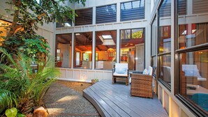 A modern building with large windows, a wooden deck, and indoor seating.