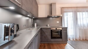 A modern kitchen with grey cabinets, a built-in oven, and a stainless steel range hood. - 175A Panoramic Apartment 24 (Ortisei)