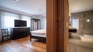 A bedroom with a bed, dresser, TV, and a wooden floor. - 175A Panoramic Apartment 24 (Ortisei)