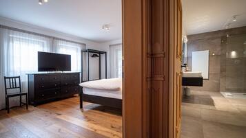 Ein Schlafzimmer mit Bett, Kommode, Fernseher und Holzboden.