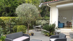 Un patio al aire libre con mobiliario de mimbre, una pequeña mesa y plantas en macetas.