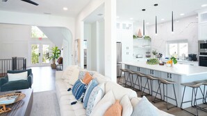 A modern kitchen with a central island, bar stools, and a dining area with a white table and chairs.