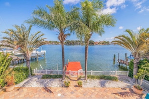 Enjoy a serene waterfront retreat with a patio area surrounded by palm trees and a view of the marina.