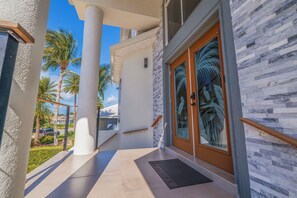 Step into a tropical haven with a sleek entrance featuring a glass door and decorative palm leaf motif.