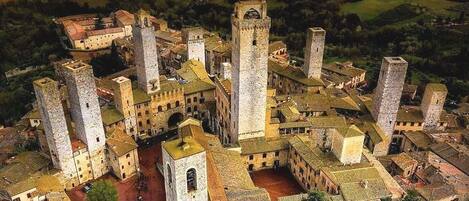 A medieval town with a prominent church featuring a tall bell tower, surrounded by smaller buildings and a hilly landscape in the background.