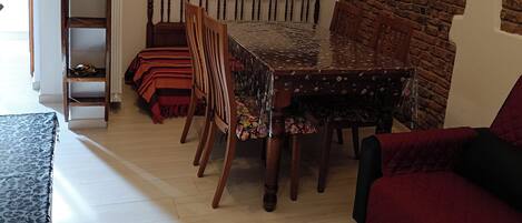 A dining area with a brick wall, a large mirror, and a wooden table with chairs.
