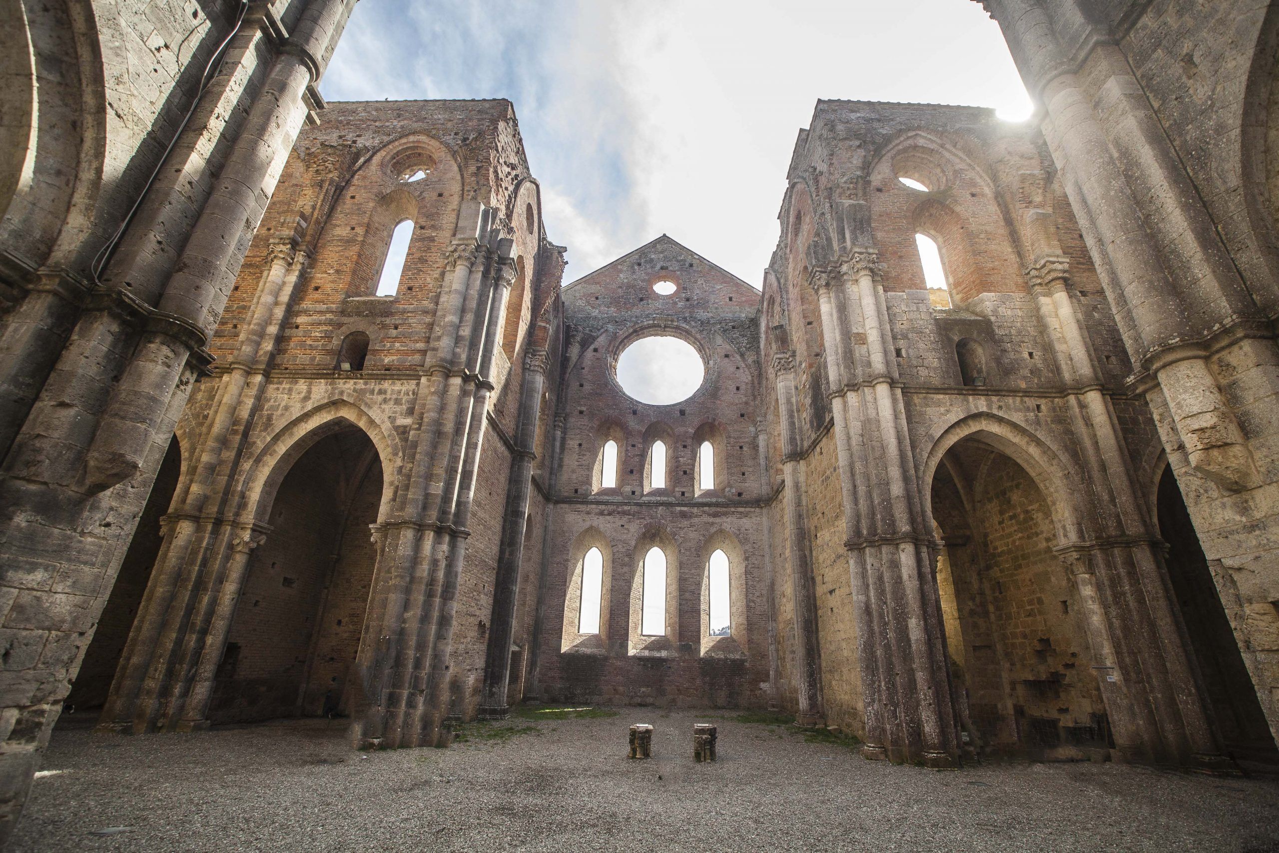 L’intérieur d’un bâtiment historique, caractérisé par de grandes arcades et une fenêtre circulaire centrale.