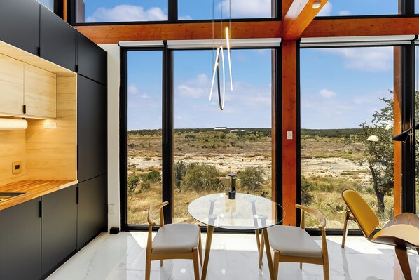 A modern kitchen with a large window, a round dining table, and two chairs.
